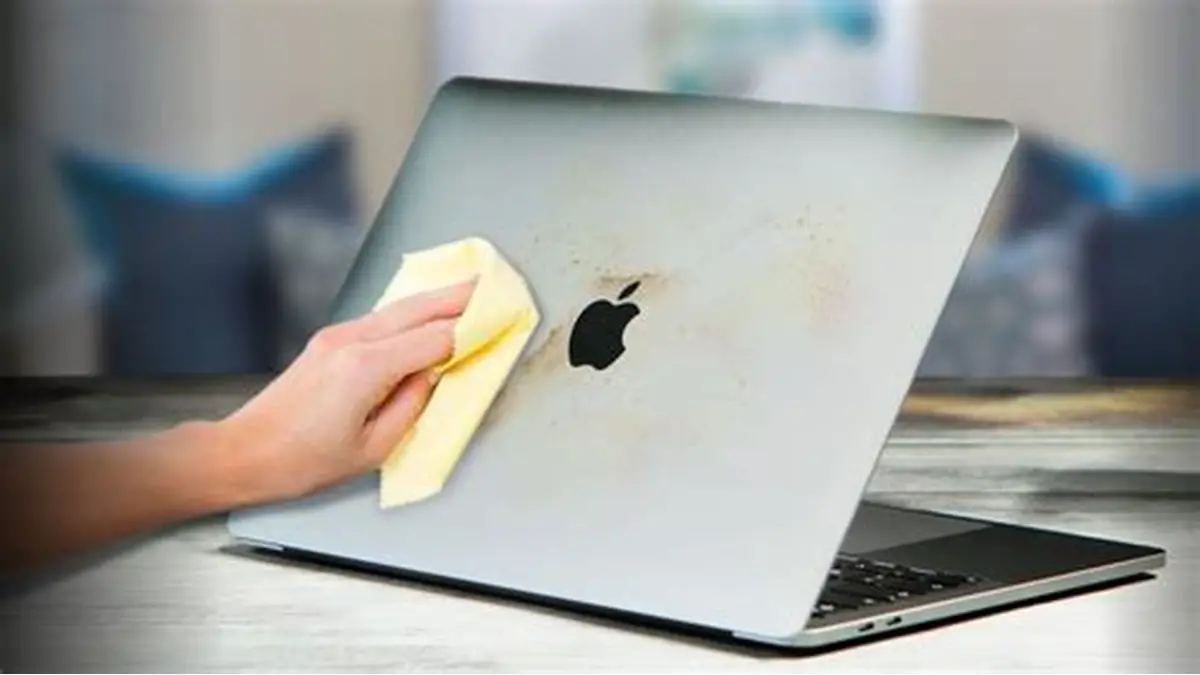 A stained laptop lid being wiped clean with a cloth