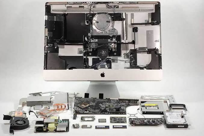 An iMac stripped down with every internal component laid out in front of it