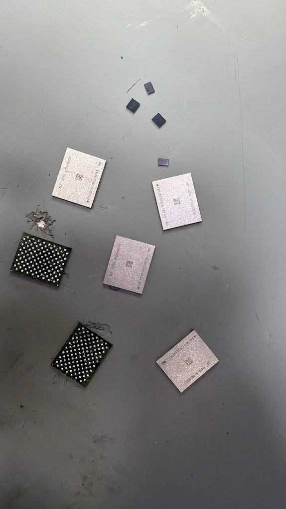 Integrated circuits removed from logic boards, showing the solder ball grids underneath