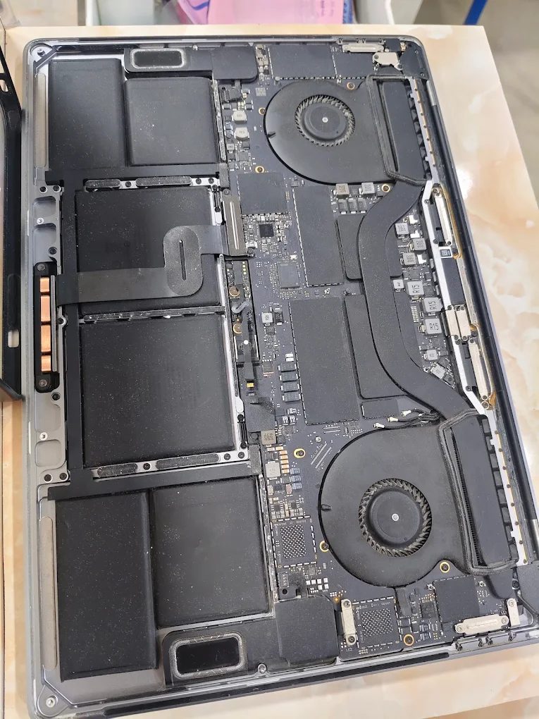 An Intel MacBook Pro with the lower case off, showing its battery cells, logic board, two fans and heat pipe